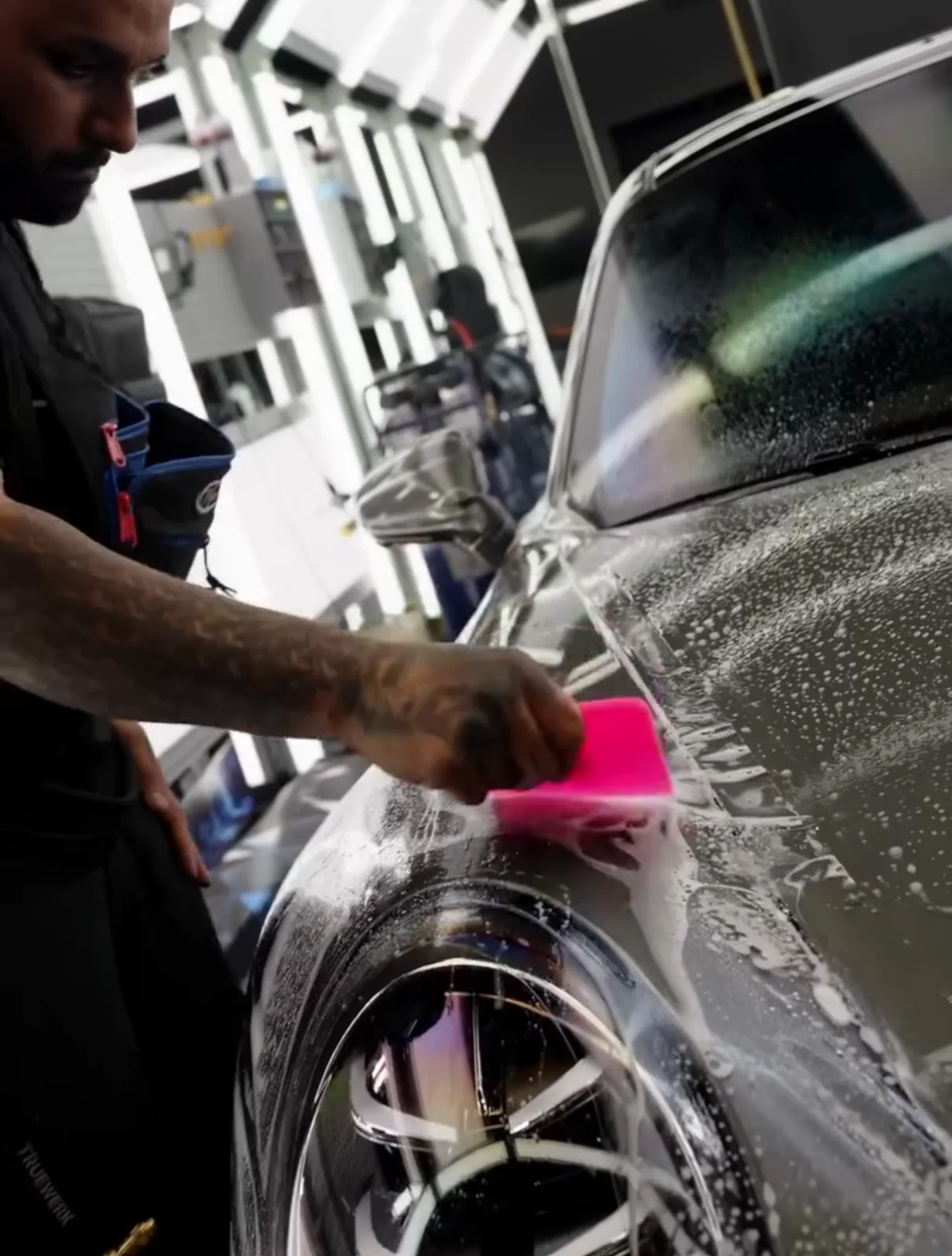 Paint protection film being installed over the front guard of a dark SUV