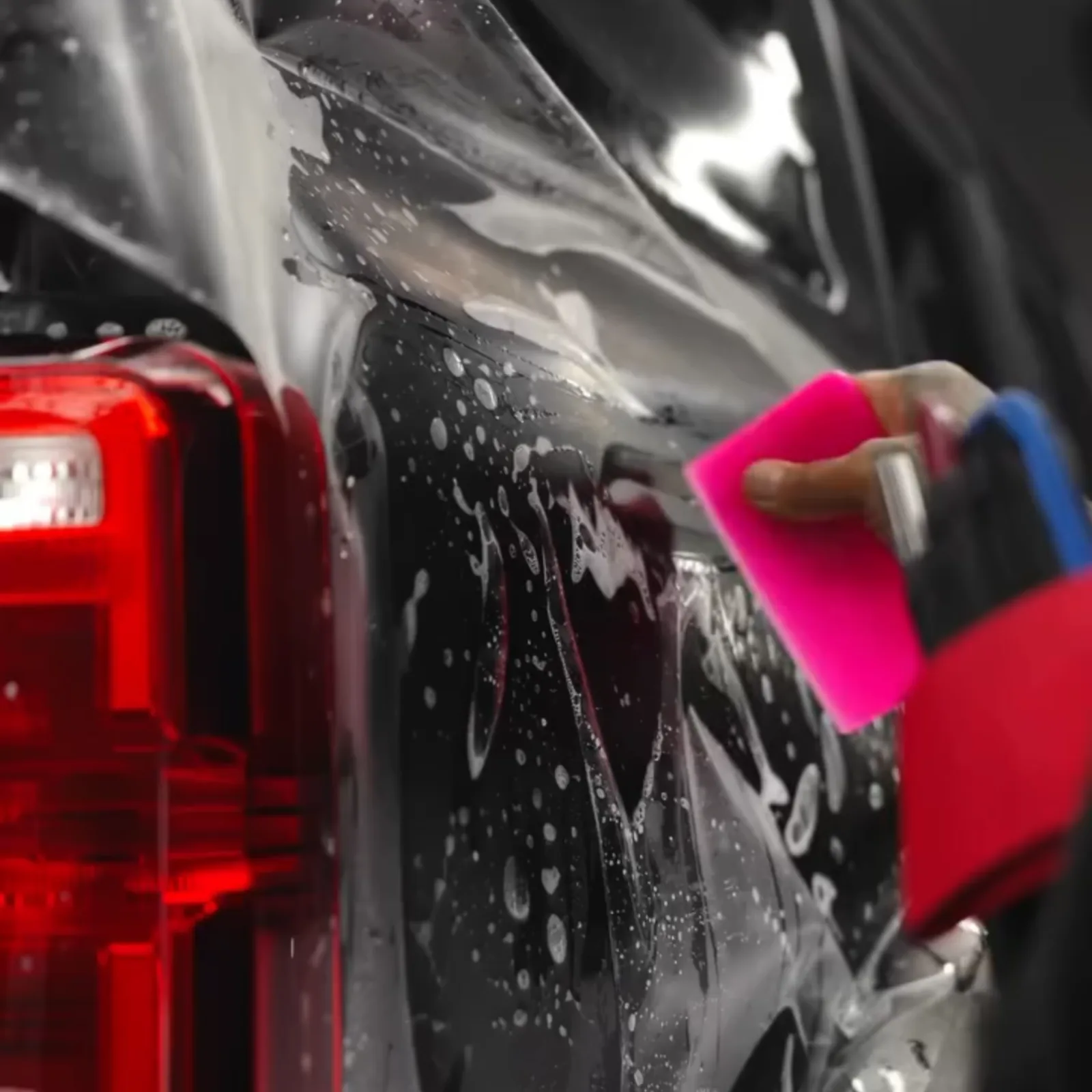 Close-up of slip solution being squeegeed out from under paint protection film